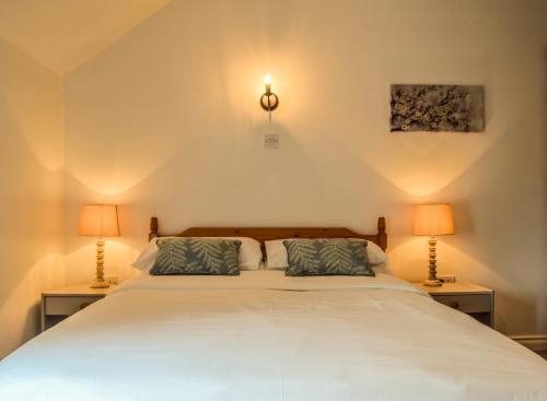 ニーナーにあるThe Waterside Cottagesのベッドルーム(白い大型ベッド、ランプ2つ付)