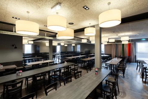 a dining room with tables and chairs and lights at a&o Frankfurt Ostend in Frankfurt/Main
