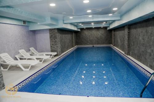 uma grande piscina com cadeiras e mesas num quarto em GM City Hotel em Baku