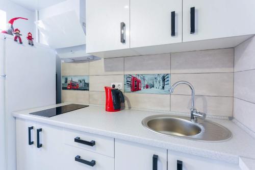 a kitchen with a sink and white cabinets at Obolon metro station in Kyiv