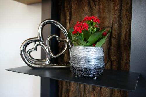 a silver vase with red flowers on a shelf at Ferienwohnungen Ellen Müller in Fischen