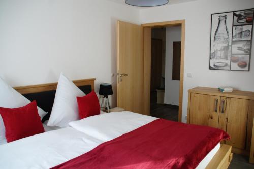 a bedroom with a bed with red and white pillows at Ferienwohnungen Ellen Müller in Fischen