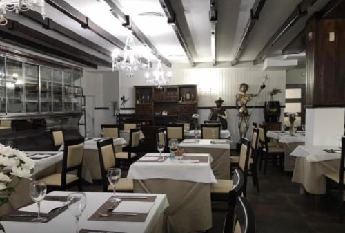 un restaurante con mesas y sillas blancas y un hombre de fondo en El Quijote, en El Toboso