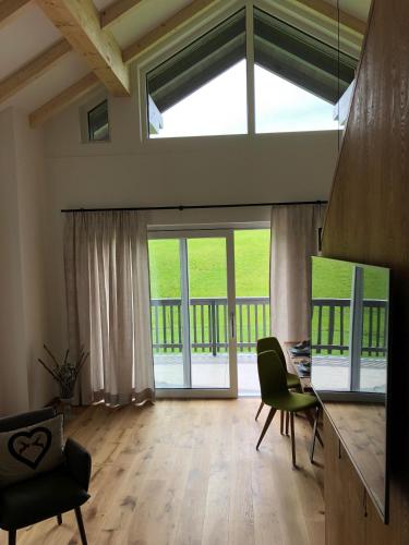 a living room with a table and chairs and large windows at Am Holzmeisterweg 31 "Erika" in Gosau