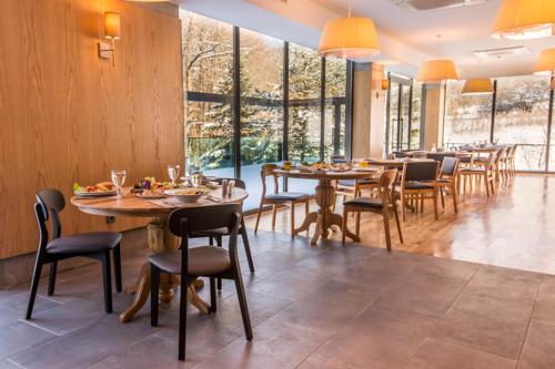 a dining room with tables and chairs and windows at Abant Lotus Otel in Akçaalan