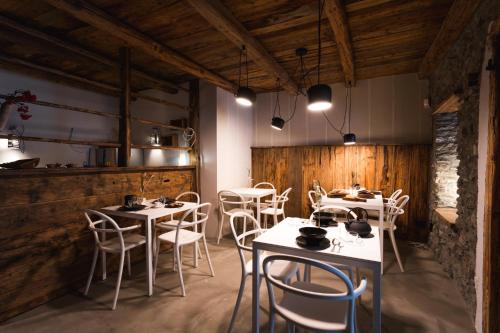 un restaurante con mesas y sillas blancas y paredes de madera en Granuit room & breakfast, en Sauze di Cesana