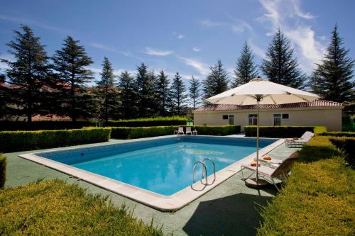 a swimming pool with an umbrella next to a house at Parador de Teruel in Teruel