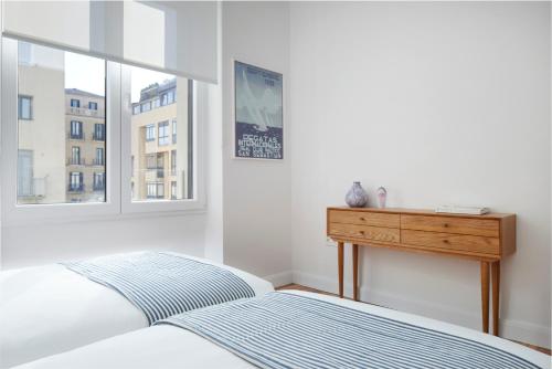 ein Schlafzimmer mit Bett, Schreibtisch und Fenster in der Unterkunft Mayflower by FeelFree Rentals in San Sebastián