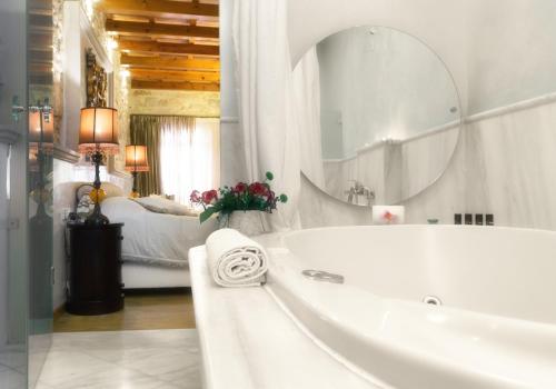 baño blanco con bañera y espejo grande en Avli Lounge Apartments, en Rethymno