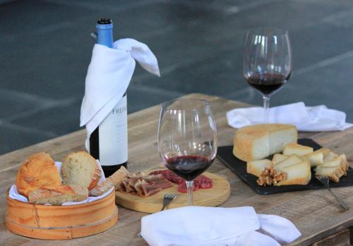 a wooden table with two glasses of wine and cheese at Amoras Country House Hotel in Proença-a-Nova