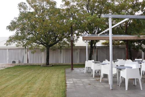 a patio with white tables and chairs in a yard at Amoras Country House Hotel in Proença-a-Nova