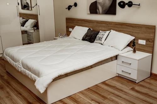 1 dormitorio con 1 cama blanca grande y cabecero de madera en Loft apartment, en Leópolis