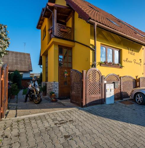 a man on a motorcycle in front of a yellow house at Vila House Family in Poprad