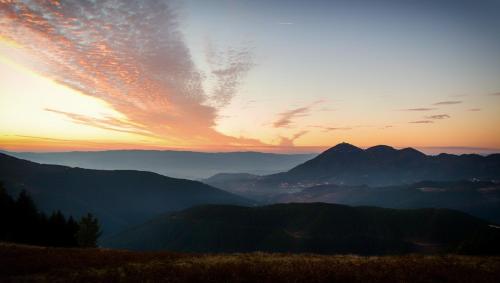 a sunset over a mountain range with the sun setting at Refúgio dos Macedos in Bilhó