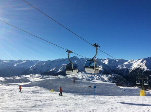 2 persone che cavalcano un impianto di risalita su una montagna innevata di Appartamento Seppi Stile Trentino a Pinzolo