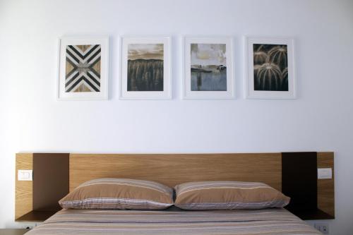 eine weiße Wand mit vier Bildern über einem Bett in der Unterkunft Appartamento Santa Lucrezia in Polignano a Mare