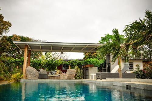 uma piscina com cadeiras e uma pérgula ao lado de uma casa em La Maracuya Panama em Playa Coronado