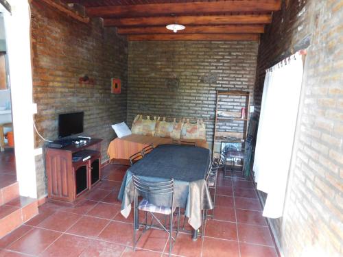 Habitación con mesa, TV y pared de ladrillo. en Cabañas las Vertientes, en Villa Parque Síquiman