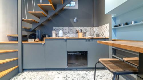 une cuisine avec des armoires bleues et un escalier dans l'établissement Midoon guest - DUPLEX D'ARCHITECT PARIS 10ème, à Paris