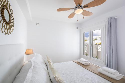 プラヤ・オンダにあるFlower Beach Suite 16の白いベッドルーム(天井ファン、ベッド付)