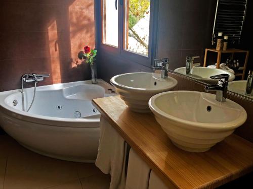 a bathroom with two sinks and a tub and two mirrors at Hotel Resort Cueva del Fraile in Cuenca