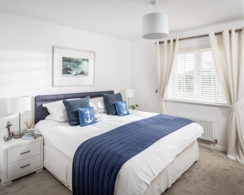 um quarto com uma cama grande e almofadas azuis em The Light House em Camber