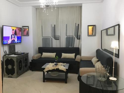 a living room with a black couch and a tv at La mer carrément à vos pieds in Hammamet