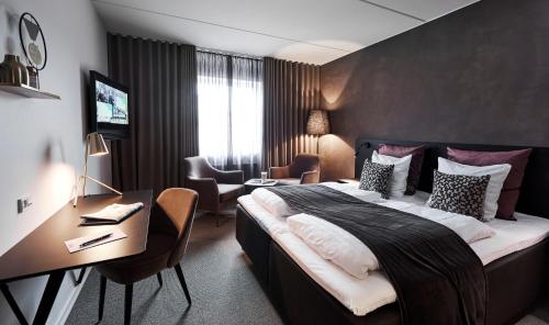 una camera d'albergo con un letto grande e una scrivania di Struer Grand Hotel a Struer