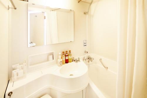 a white bathroom with a sink and a shower at Shinagawa Prince Hotel East Tower in Tokyo