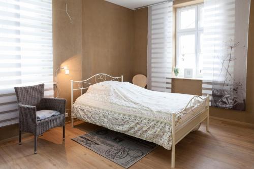 a bedroom with a bed and a chair and windows at Pension-City-Kontor-Erfurt in Erfurt