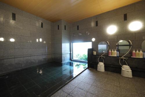 baño con bañera, 2 espejos y ventana en Hotel Route-Inn Aomori Chuo Inter en Aomori