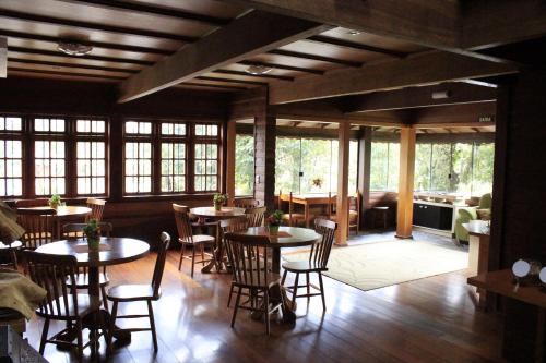 un comedor con mesas, sillas y ventanas en Pousada Floresta Negra, en Canela