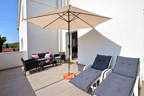a patio with chairs and an umbrella on a balcony at Apartment Kristina in Murter