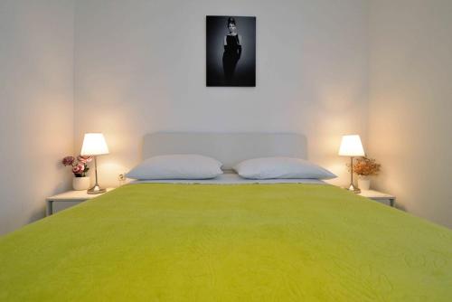 a bedroom with a large green bed with two lamps at Apartment Kristina in Murter