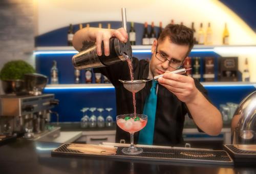 a man pouring a drink into a martini glass at Grand Laola Spa in Pobierowo