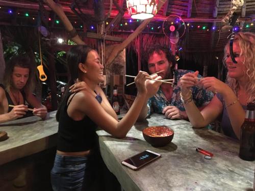 a group of people sitting at a bar eating chopsticks at Freedom home in Ko Chang