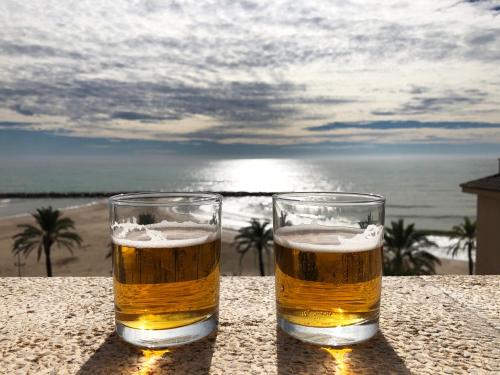 dos vasos de cerveza sentados en una mesa cerca de la playa en Espectacular ático dúplex con vistas al mar en Cunit
