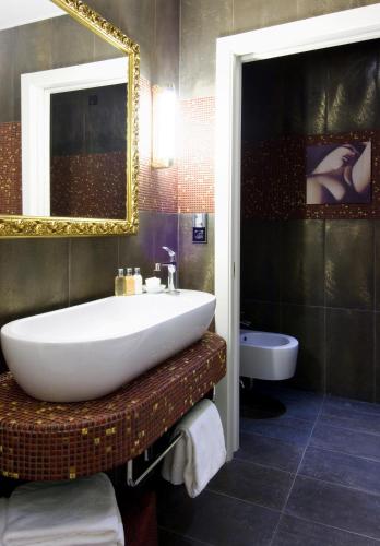a bathroom with a sink and a mirror and a tub at Parc Hotel Flora S in Riva del Garda