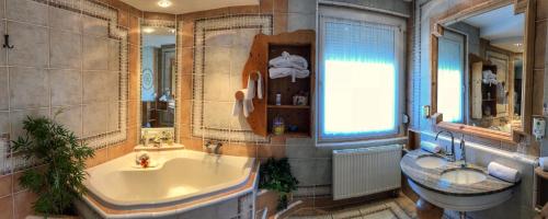 a bathroom with a large tub and a sink at Sporthotel Kapfenberg in Kapfenberg
