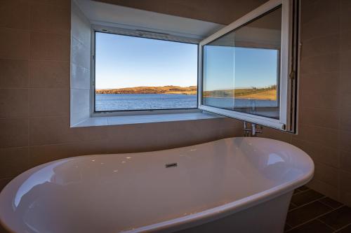 a bath tub in a bathroom with a window at Lochside in Staffin