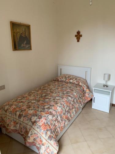 a bed in a bedroom with a cross on the wall at Istituto SS Salvatore in Orvieto