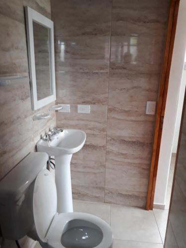 a bathroom with a sink and a toilet and a mirror at Aqua Duplex in Villa Carlos Paz