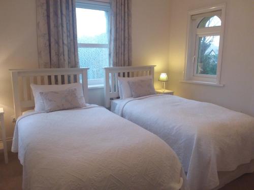 two white beds in a room with a window at Chine Side in Shanklin