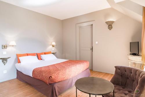 a bedroom with a bed and a table and a couch at Hôtel Restaurant Spa Le Sauvage in Besançon