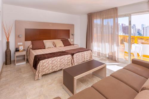 um quarto de hotel com uma cama e um sofá em Hotel & SPA Dynastic em Benidorm