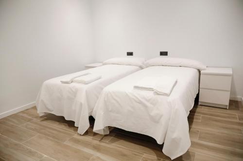 2 camas en una habitación con sábanas blancas en SM Apartments Station, en Lleida