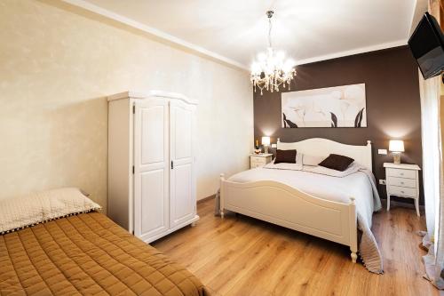 Un dormitorio con una gran cama blanca y una lámpara de araña. en La Rocchetta en Valeggio sul Mincio