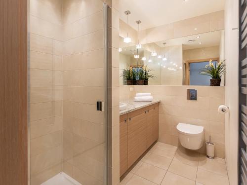 ein Bad mit einer Dusche, einem WC und einem Waschbecken in der Unterkunft VacationClub - Bałtycka 10 Apartament 9 in Świnoujście