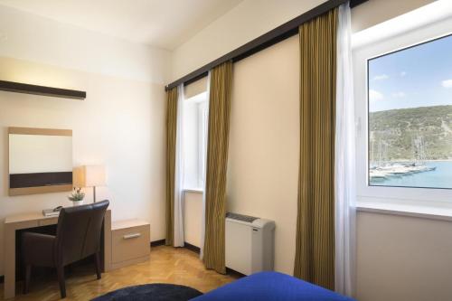 ein Hotelzimmer mit einem Schreibtisch und einem Fenster in der Unterkunft Apartment ACI Marina CRES in Cres