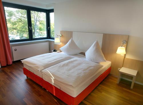 ein Schlafzimmer mit einem großen Bett mit weißer Bettwäsche und Kissen in der Unterkunft Hotel Ullrich in Elfershausen